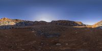 a panorama lensing image of a rock formation near the mountains at sunrise time in the far distance