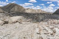 some rocks that are on the ground in the mountains and under a sky with clouds