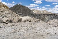 some rocks that are on the ground in the mountains and under a sky with clouds