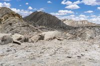 some rocks that are on the ground in the mountains and under a sky with clouds