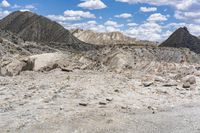 some rocks that are on the ground in the mountains and under a sky with clouds