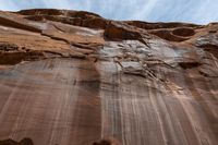 the sun beams down on a wall of rock with rocks and rocks around it in front of a blue sky