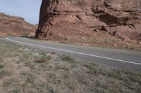 a person riding a motorcycle along a narrow road through rocks and sand cliffs a grassy area on both sides