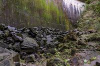 rocks along the path are piled up with moss and moss growing on the walls of a dam wall