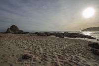 the sun is setting over the sea near rocky beachfronts with several sand castles