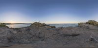 view of rocky cliff with ocean in background and sky in foreground by ocean shore