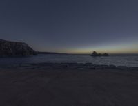 a picture of a rocky coast at dusk with stars and the sun setting in the background