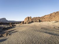 the desert area is covered in large rocks and boulders at night time with a small hill behind the sand