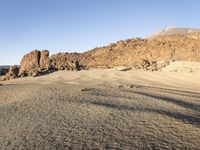 the desert area is covered in large rocks and boulders at night time with a small hill behind the sand