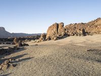 the desert area is covered in large rocks and boulders at night time with a small hill behind the sand