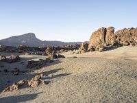 the desert area is covered in large rocks and boulders at night time with a small hill behind the sand