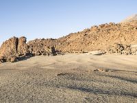 the desert area is covered in large rocks and boulders at night time with a small hill behind the sand