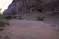 a red frisbee sitting in dirt next to a rocky cliff side area with rocks