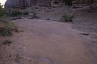 a red frisbee sitting in dirt next to a rocky cliff side area with rocks