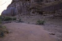 a red frisbee sitting in dirt next to a rocky cliff side area with rocks