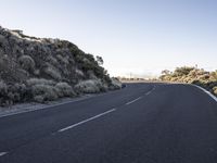 this is a empty road that is very rocky and dusty with a small hill in the background