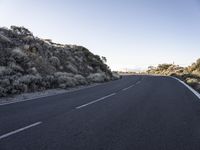 this is a empty road that is very rocky and dusty with a small hill in the background