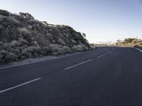 this is a empty road that is very rocky and dusty with a small hill in the background