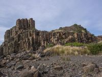 this is an image of a rocky hill with large rocks and grass in front of it