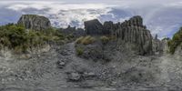 a rocky hillside area with tall and narrow rocks and trees, as well as a waterhole