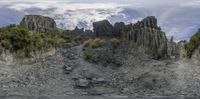 a rocky hillside area with tall and narrow rocks and trees, as well as a waterhole