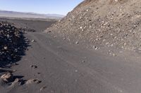 there is a large pile of rocks along the dirt path and mountain of rocks and stones