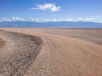 an empty area with some rocky ground in the middle of it and mountains behind it