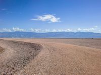 an empty area with some rocky ground in the middle of it and mountains behind it