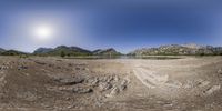 this is an 360 - angle of a rocky landscape with mountains and lake in the distance