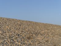 a man with his bike is walking over some rocks at the top of a hill