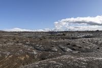 a big open rocky area with some blue skies in the background and a lone white horse on it