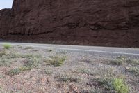 a person riding a motorcycle along a narrow road through rocks and sand cliffs a grassy area on both sides