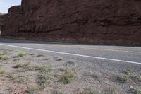 a person riding a motorcycle along a narrow road through rocks and sand cliffs a grassy area on both sides