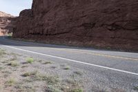 a person riding a motorcycle along a narrow road through rocks and sand cliffs a grassy area on both sides