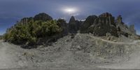 a very strange, dark rocky mountain landscape with rocks and trees in the foreground