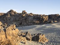 a rocky outcropping sits near rocks and sand in the middle of a desert