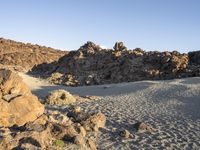 a rocky outcropping sits near rocks and sand in the middle of a desert