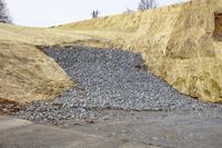 some rocks that are sitting in the dirt area of a building in the middle of a hill