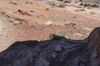 man riding on rocky road with saddle in desert area with small stream in distance on sunny day