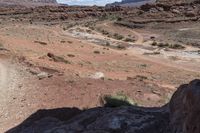 man riding on rocky road with saddle in desert area with small stream in distance on sunny day