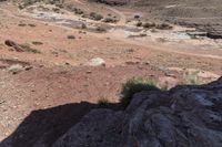 man riding on rocky road with saddle in desert area with small stream in distance on sunny day