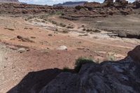 man riding on rocky road with saddle in desert area with small stream in distance on sunny day