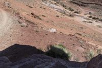 man riding on rocky road with saddle in desert area with small stream in distance on sunny day