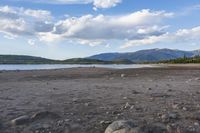 rocky shore and mountain range on the coast of a body of water with rocks in it