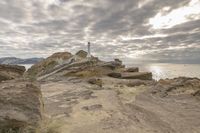 Rocky Shoreline with Lighthouse under a Gloomy Sky