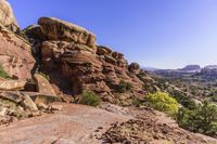 rocks and trees along a path in arches rock state park, utah, usa, in the background is a valley full of red rocks