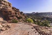 rocks and trees along a path in arches rock state park, utah, usa, in the background is a valley full of red rocks