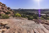 rocks and trees along a path in arches rock state park, utah, usa, in the background is a valley full of red rocks
