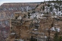 a rocky cliff covered in snow in the mountains near an area with trees and cliffs