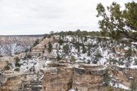 a rocky cliff covered in snow in the mountains near an area with trees and cliffs